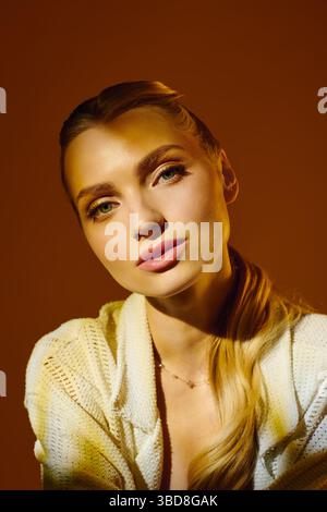 Captivating young woman poses gracefully, showcasing her beauty and refined style with warm tones. Stock Photo