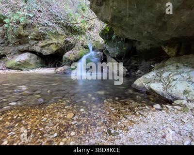 Stream flowing among the rocks with a small waterfall in the background, in the province of Pescara Stock Photo