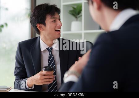 Business Engagement and Networking. A joyful professional interaction between two colleagues discussing ideas over coffee in a modern office setting. Stock Photo