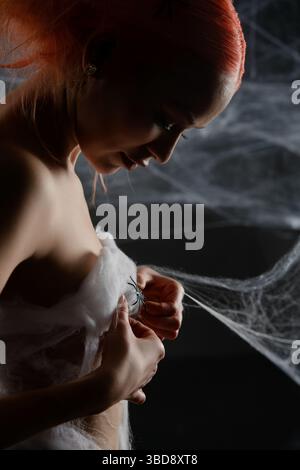 Red-haired woman trapped in a net, revealing her beauty amid the web Stock Photo