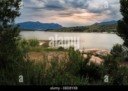 Landscape with dramatic sky at the Beniarres reservoir during sunset on a stormy day, Spain Stock Photo