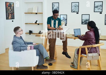 Multiracial professionals engaged in meeting, discussing strategy and working on laptops in art gallery Stock Photo