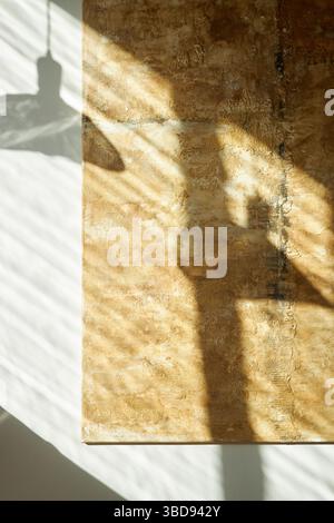 Shadows from natural sunlight cast intricate patterns on textured wall surface creating an artistic interplay of light and shadow Stock Photo
