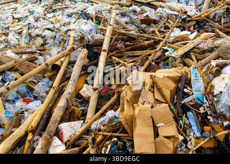 Bali, Indonesia - Dec 22, 2024: Beach is covered in trash and debris. The scene is chaotic and disorganized, with people scattered around the area. Sc Stock Photo