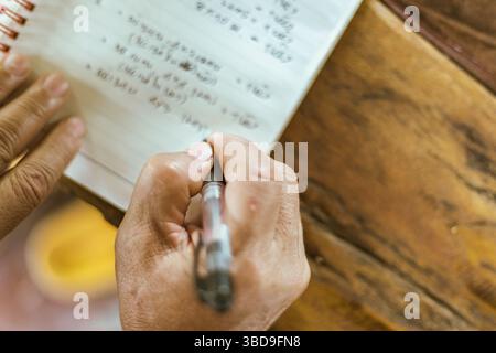 A hand writing on a notebook on a table, selective focus Stock Photo