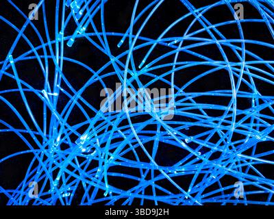 abstract arrangement of blue lighted or lit LED lights on  wires curled up on a black background Stock Photo