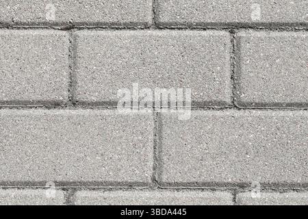 Gray concrete paving texture. Urban sidewalk pattern. Clean flat bricks in sunlight. Rough industrial surface. Minimalist structure and design. Stock Photo