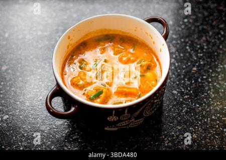 Massaman curry in a clay bowl with handles. Hot spicy Thai dish. Stock Photo