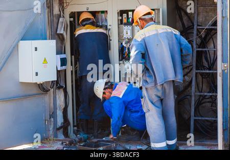 Electrician workers are making repairs in the electrical panel room. Stock Photo