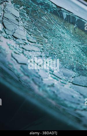 Detailed view of shattered safety glass on a car windshield. Broken glass patterns radiate from central impact point. Stock Photo