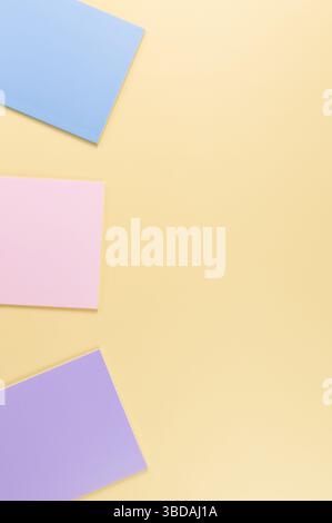 Top view of pink, purple and blue notebooks on yellow background. School, office wallpaper. Flat lay, copy space. Stock Photo