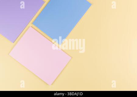 Top view of pink, purple and blue notebooks on yellow background. School, office wallpaper. Flat lay, copy space. Stock Photo