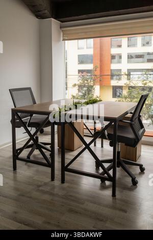 A modern conference room arranged with sleek tables and chairs, illuminated by a large window that enhances the professional and elegant design. Stock Photo
