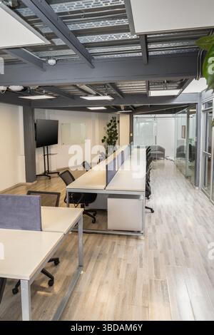 An airy coworking environment with communal long tables and comfortable chairs, fostering collaboration and creativity among professionals in a modern Stock Photo