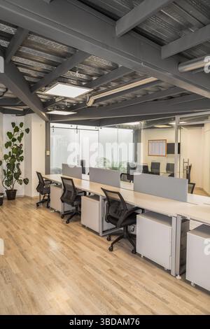 A bright office space featuring multiple modern cubicles where employees work diligently, highlighting productivity and organized workspace design. Stock Photo