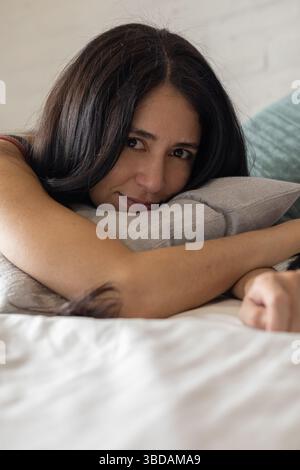 Face down with arms wrapped around a pillow, she lies still, as if seeking comfort or hiding from the world in quiet retreat. Stock Photo