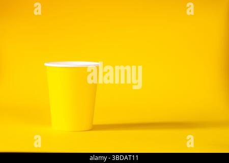Yellow paper cup on yellow background. copy space Stock Photo