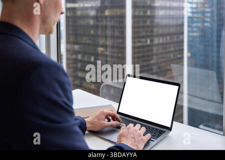 Business man using laptop in office sitting at desk. Mock up screen. Stock Photo