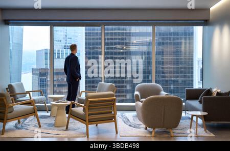 Young business man wearing suit thinking of future standing in big office. Stock Photo