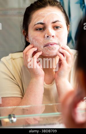 Side view of female gently cleansing and massaging face with cleansing foam. Useful for beauty brands, skincare steps, or hygiene-related content. Int Stock Photo