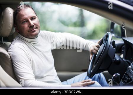 Smiling middle aged handsome man sitting in the car Stock Photo