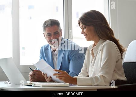 Two executives team working on laptop discussing documents at office meeting. Stock Photo