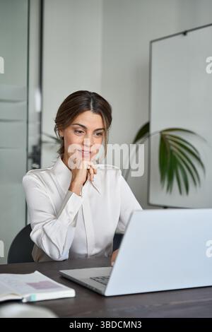 Busy mature professional business woman working on computer in office. Stock Photo