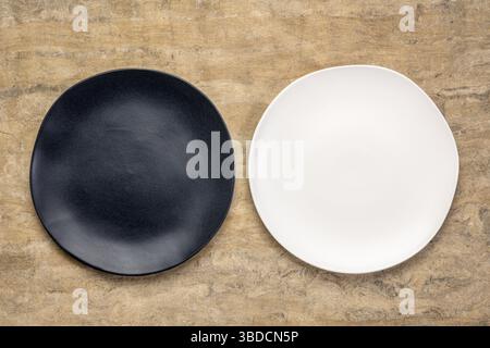 Black and white ceramic plates with an irregular edge on a buckskin handmade Huun Mayan paper Stock Photo