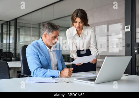 Two busy mid aged business leaders working together in office at meeting. Stock Photo