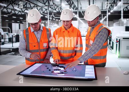 Automotive Engineers Collaborate On Electric Vehicle Design At Manufacturing Plant. Stock Photo