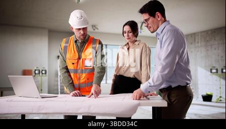 Engineer And Architect Inspecting Blueprint With Young Couple In Home. Stock Photo