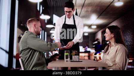 Young Couple Paying Their Bill Using Credit Card At Restaurant. Stock Photo