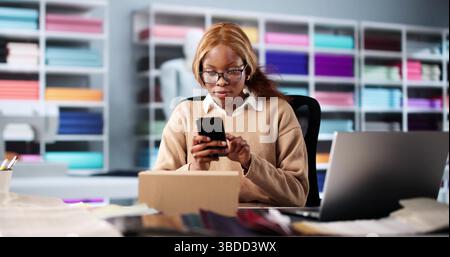 Innovative Woman At Her Online Fashion Shop Using Smartphone Creatively. Stock Photo