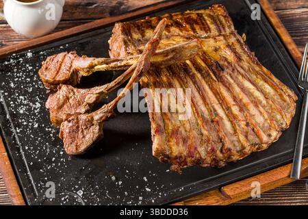 Lamb racks grilled with herbs and sauce on a stone board Stock Photo