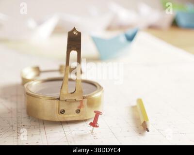 Close up of a compass and location marking with a red pin on sea map. Adventure, discovery, navigation, communication, logistics, geography, transport Stock Photo