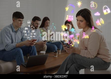 Internet addicted friends using mobile phones instead of spending time together in room. Different icons flying out of devices Stock Photo