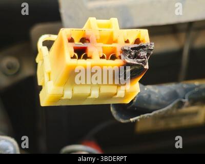 A burnt plug in the car electricity system connected to the wires that initiates electric current to car devices like air conditioner, electricity haz Stock Photo
