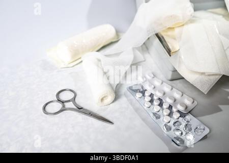 Medical supplies like bandages, plasters, pills and scissors from a first aid kit or home medicine chest on a light gray background, copy space, selec Stock Photo