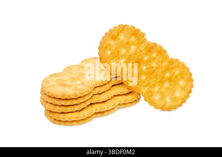 A close-up studio shot of a neat stack of golden brown, round, saltine crackers with visible salt crystals, one of which is leaning against the stack, Stock Photo