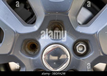 A close up view of the rim and wheel of a car with two broken lug nuts Stock Photo