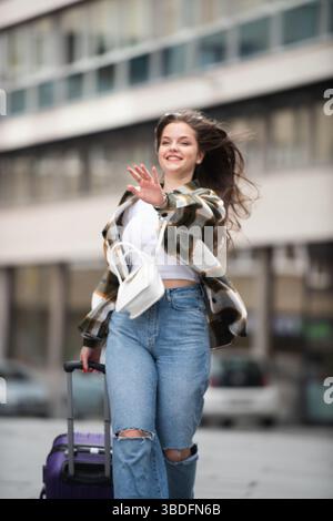 Young Woman Joyfully Walking with Luggage.  Stock Photo