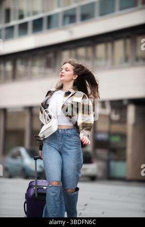 Young Woman Joyfully Walking with Luggage.  Stock Photo