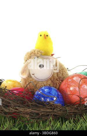 Easter nest with Easter eggs, sheep and chicks on a green flower meadow Stock Photo