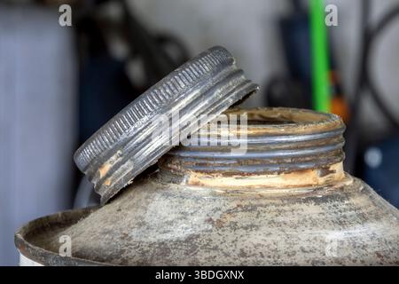 Side view of a dusty tin bottle with a rusty screw cap, half open. Patina and rust speak of industry, old workshops, and a long-forgotten past. Stock Photo