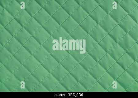 Checkered, diamond stitching pattern, green quilted fabric background. Blanket or puffer jacket, stitch rhombus texture close up, macro. Wallpaper, ba Stock Photo