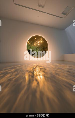 A round mirror on the wall casts warm light reflections onto the floor in an art space, Schauwerk Sindelfingen, Germany, Europe Stock Photo