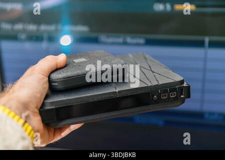 Paris, France - Feb 17, 2025: A hand holds two Orange Livebox internet TV routers, with an older generation box at the bottom featuring buttons and po Stock Photo
