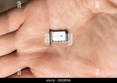 Paris, France - Apr 19, 2025: A close-up view of a nano SIM card and tray labeled Bouygues Telecom resting on an open male hand, with visible card num Stock Photo