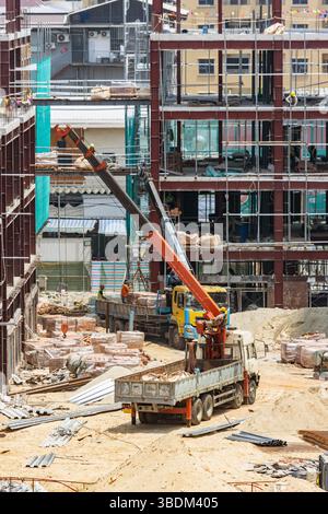 Active construction site with workers, cranes, and scaffolding on multi-level buildings under construction Stock Photo