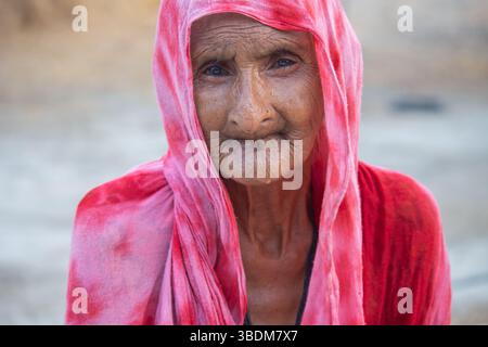Portrait of an Elderly Woman in a Red Traditional Scarf, Smiling with Grace in a Rural Setting Stock Photo